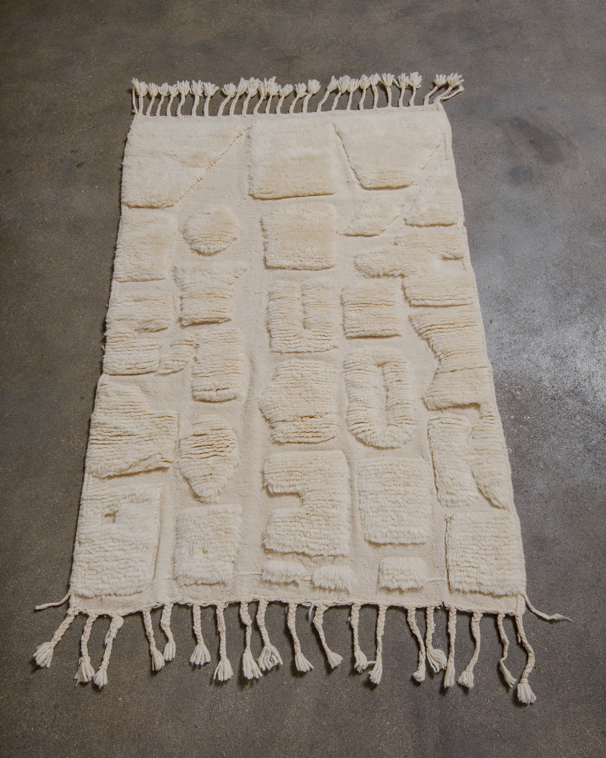 Textured Berberlin Finest cream rug with tassels on a gray floor